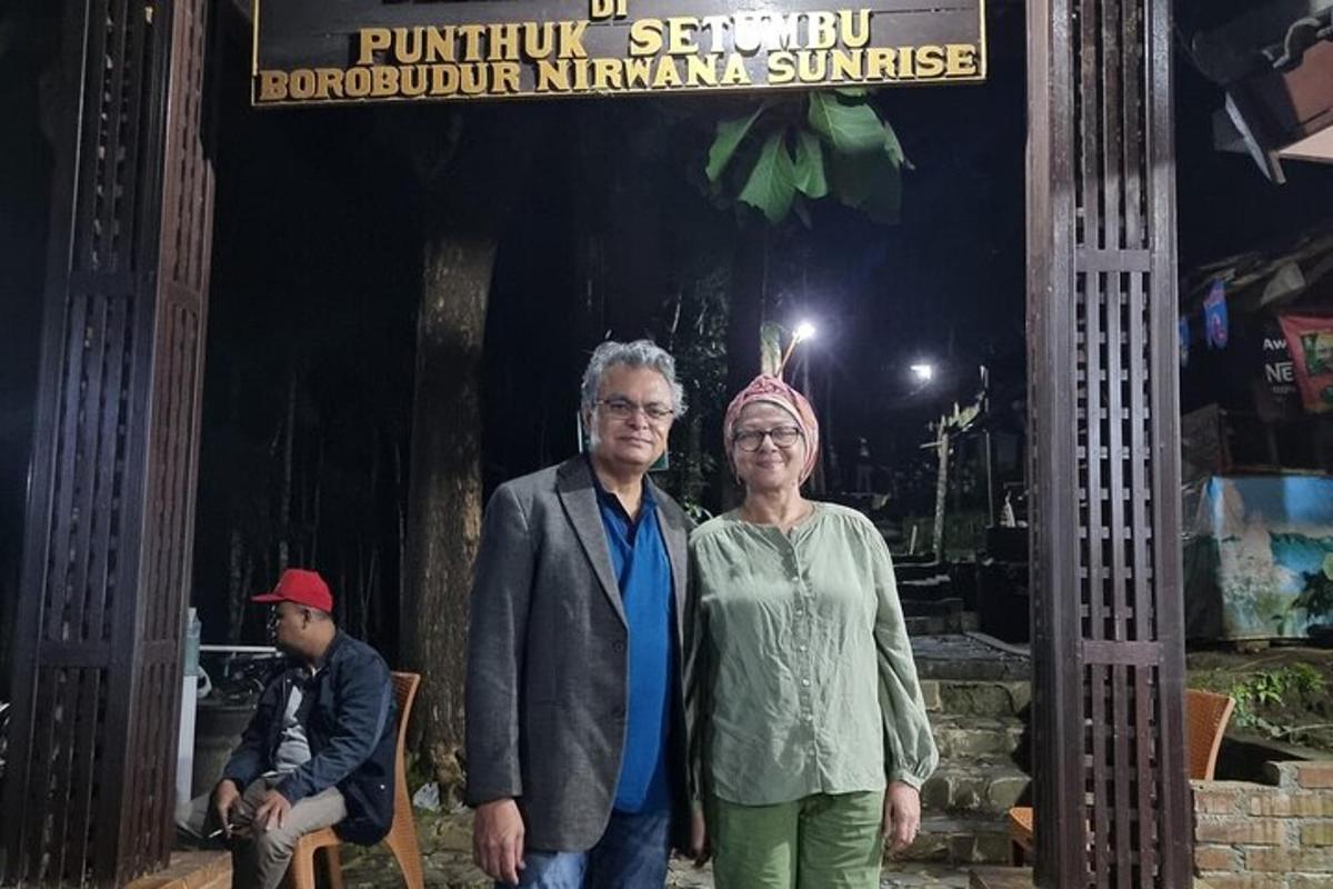 un bărbat și o femeie stând în fața unui semn