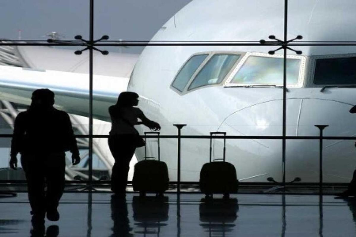due persone con i bagagli che camminano verso un aereo