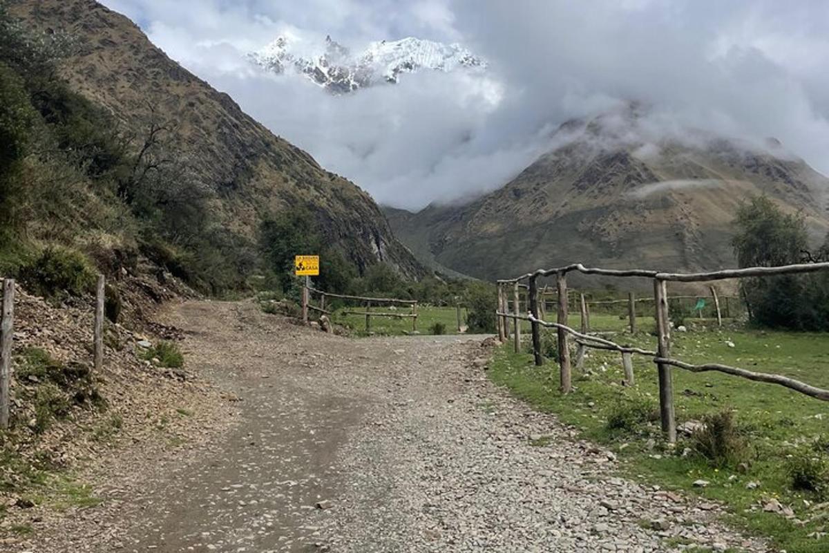un camí de terra amb una tanca i una muntanya