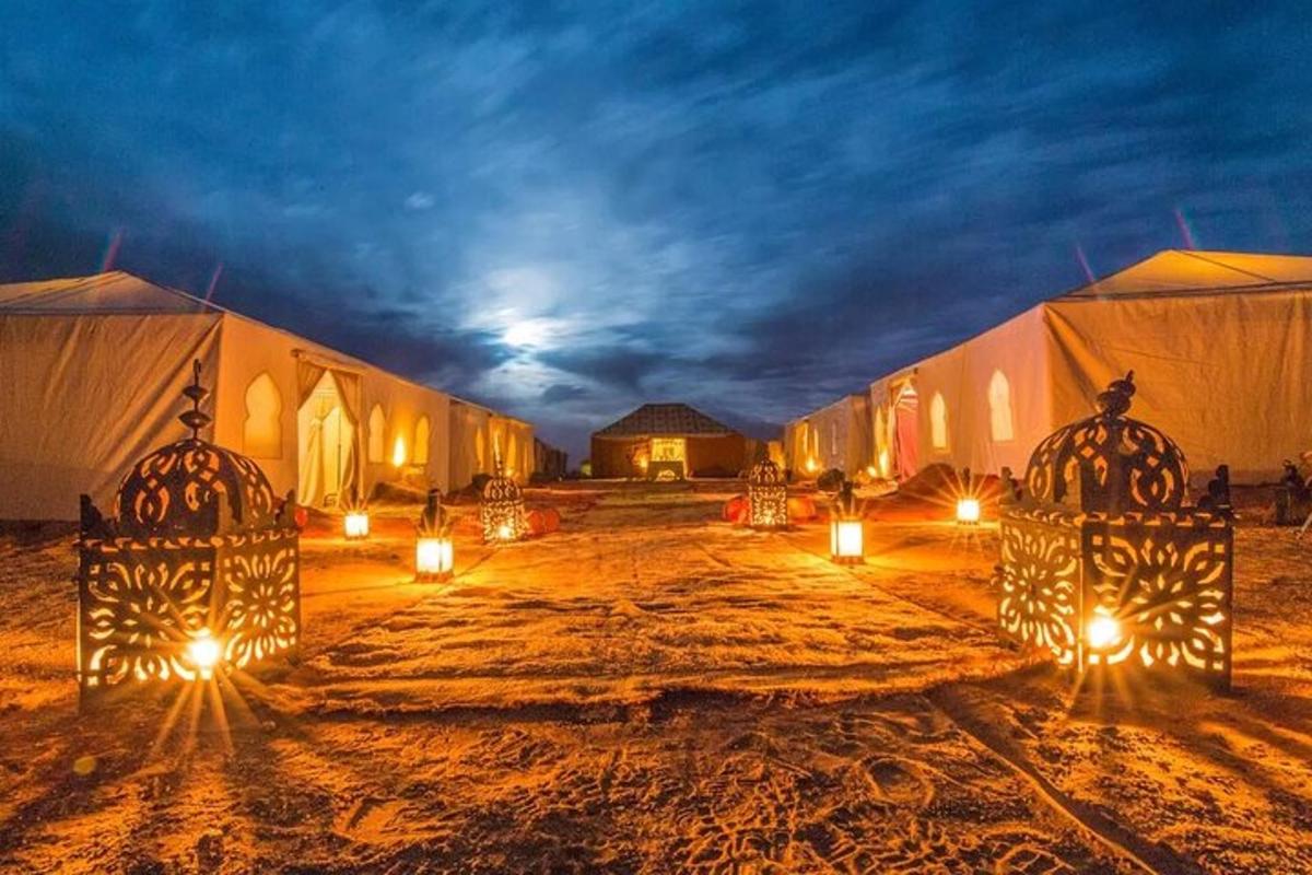 a group of tents with lights in the desert at night