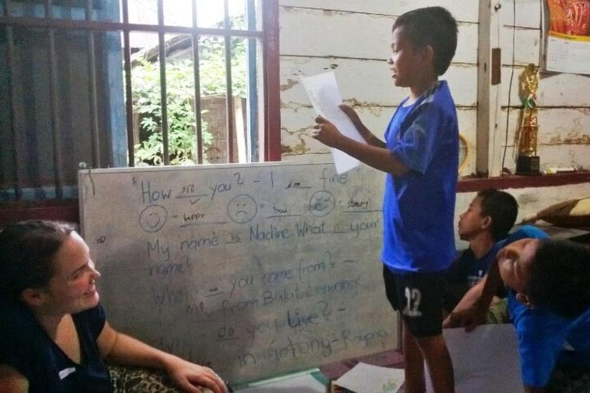 un ragazzino in piedi accanto a una lavagna con delle scritte sopra