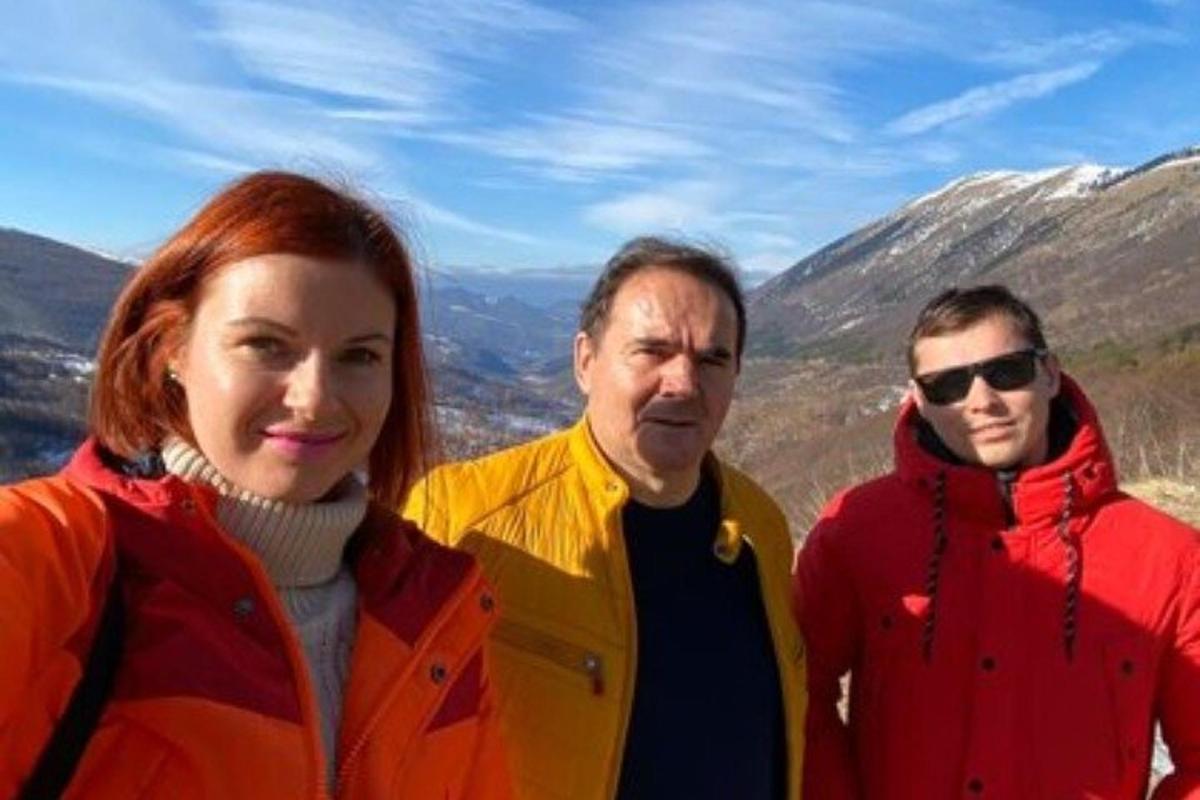 dva muži a žena stojící na vrcholu hory