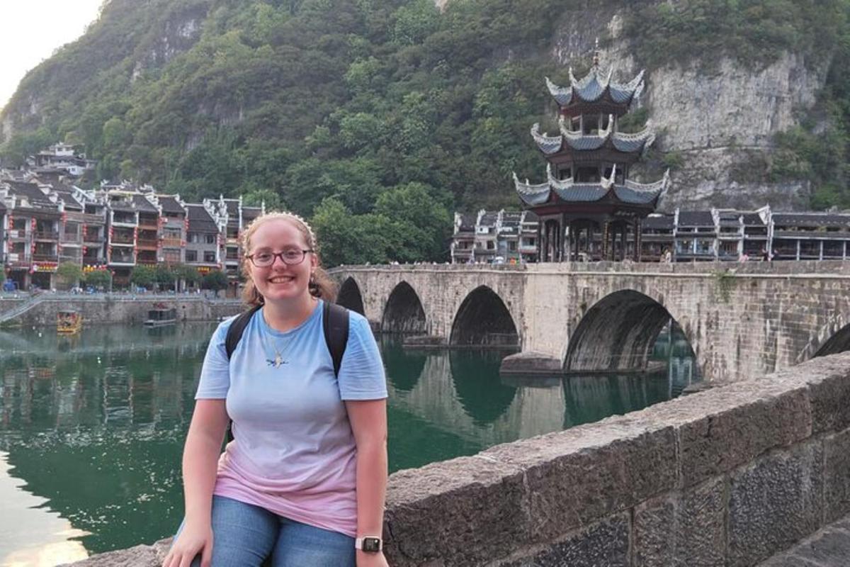 a woman sitting on a wall next to a bridge