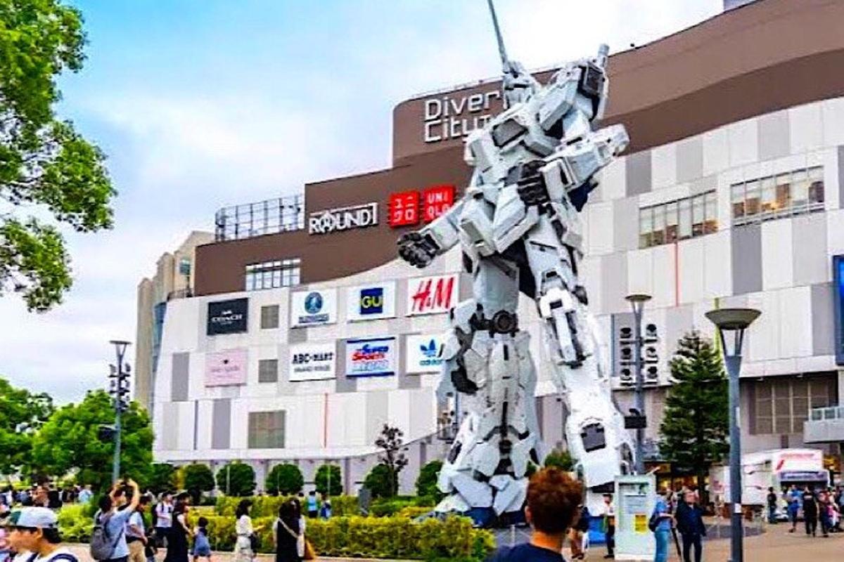 un uomo in piedi davanti a un edificio con una statua di robot