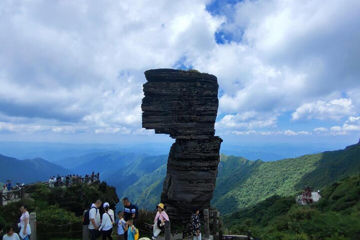 a group of people standing next to a tall rock formation