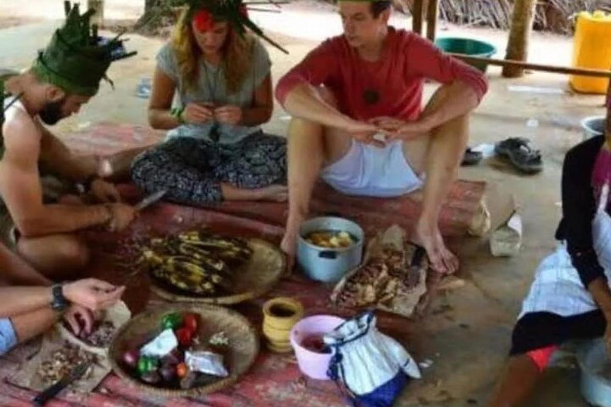 một nhóm người đang ngồi trên mặt đất với thức ăn