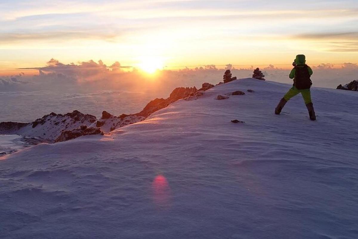 uma pessoa em pé no topo de uma montanha coberta de neve