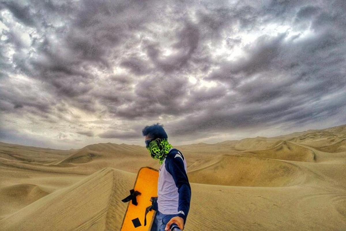 Un hombre parado en el desierto sosteniendo una tabla de snowboard.