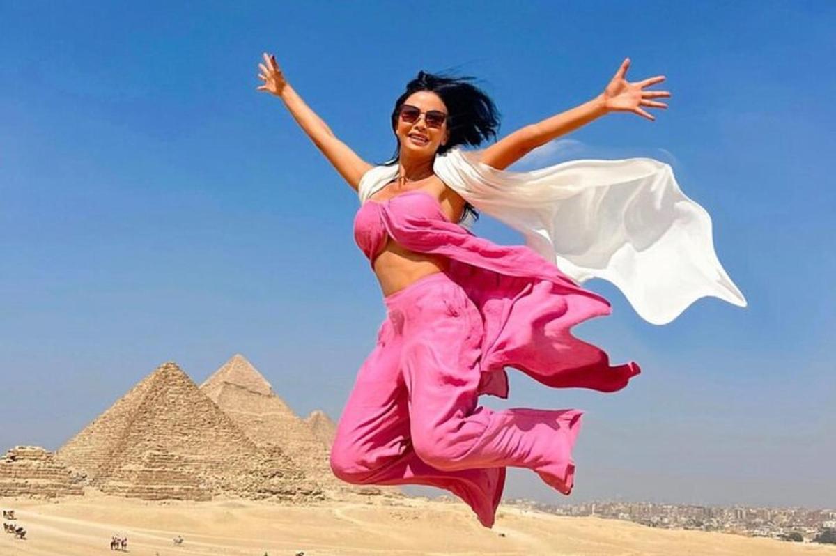 žena skákající do vzduchu před pyramidami