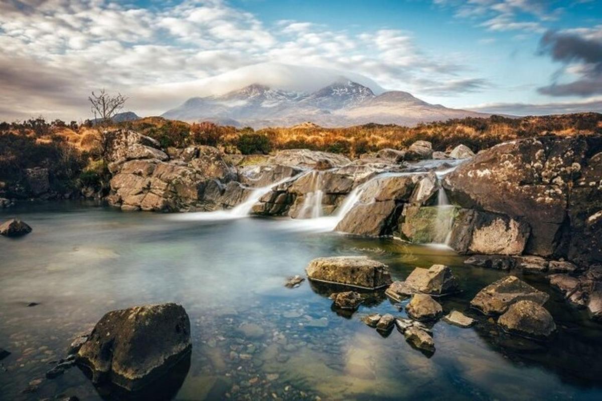 air terjun di latar depan dengan gunung di latar belakang