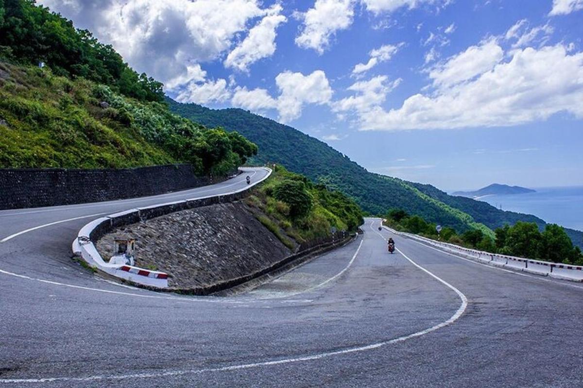 un drum șerpuitor pe un deal cu o persoană care merge pe o motocicletă