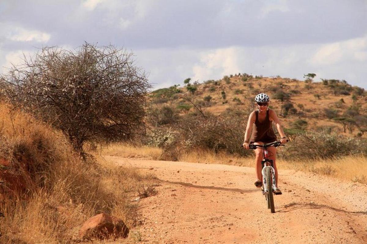 um homem andando de bicicleta em uma estrada de terra