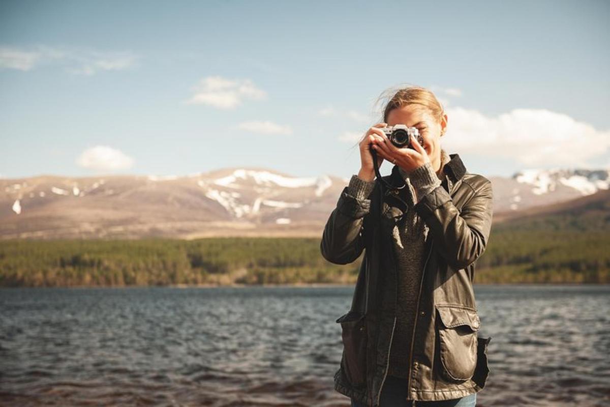 sieviete fotografē ezeru ar kameru