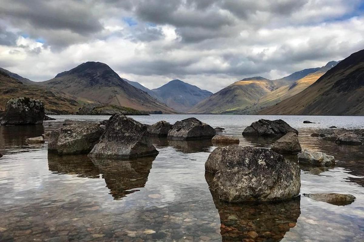 a lake with some rocks in the water with mountains