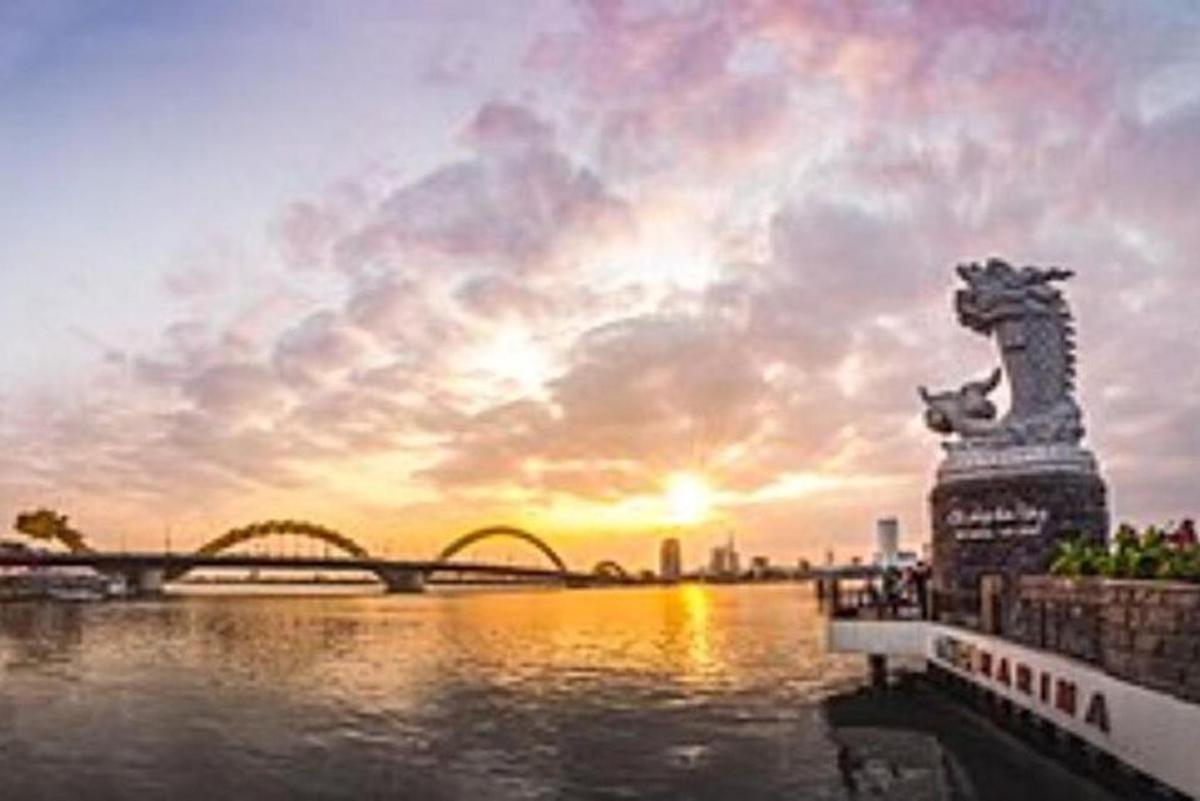 Una puesta de sol sobre un río con un puente al fondo
