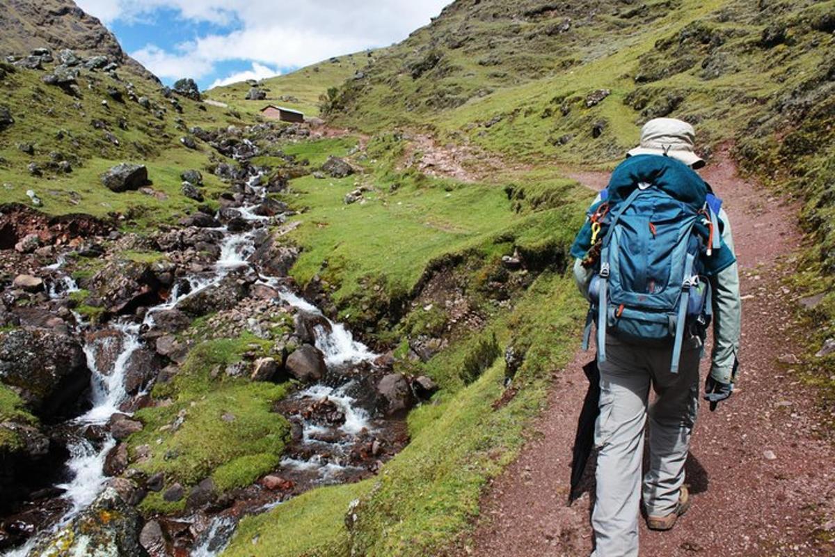 un uomo con uno zaino che cammina lungo un sentiero di montagna