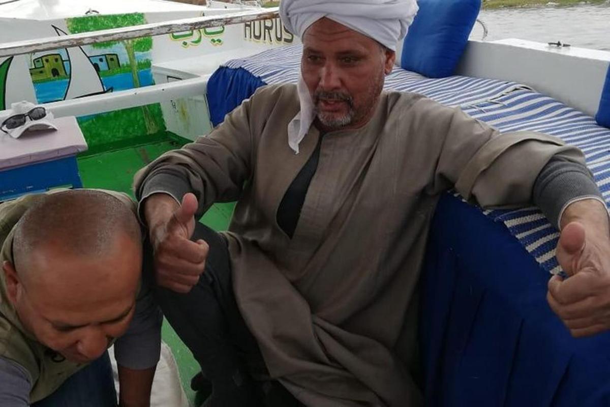 muž sediaci na lodi a ukazujúci palec hore