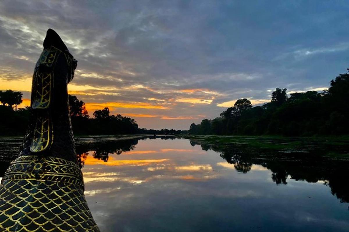 un vaixell en un riu amb una posta de sol al fons