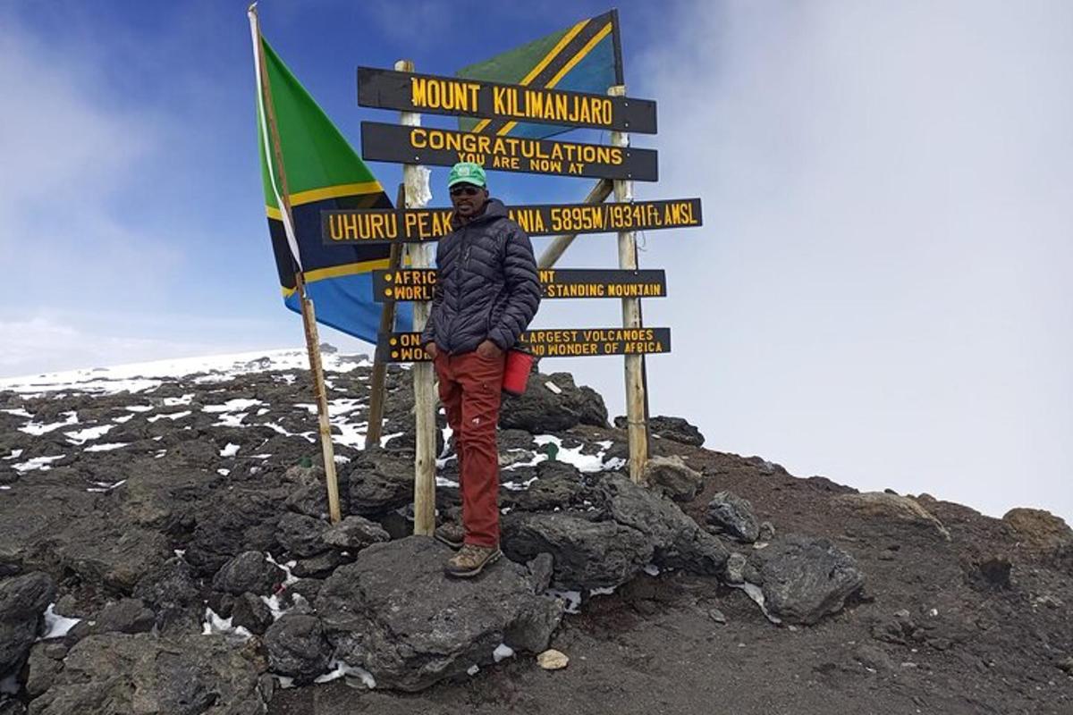 seseorang berdiri di depan tanda di gunung