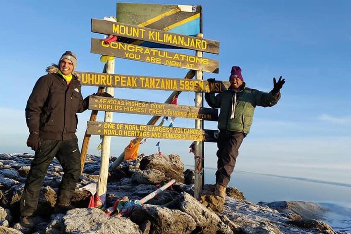 kaks meest seisavad mäe tipus sildi kõrval