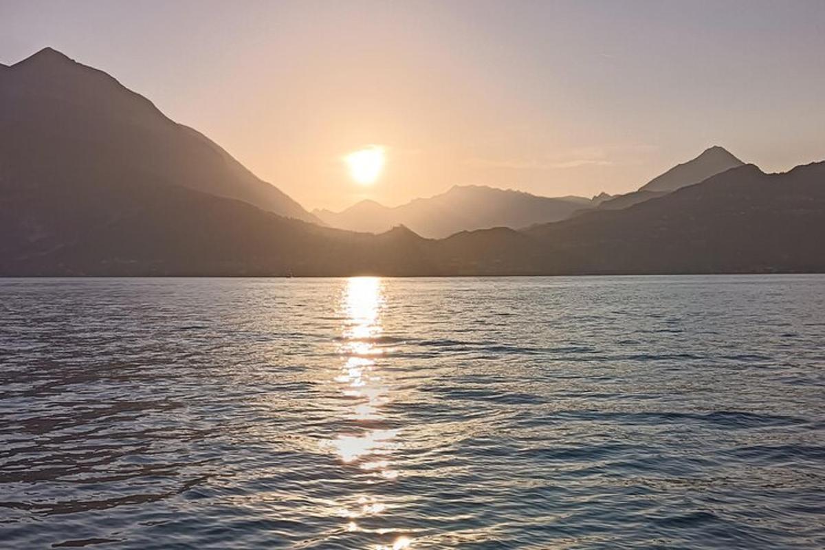 un tramonto sull'acqua con le montagne sullo sfondo