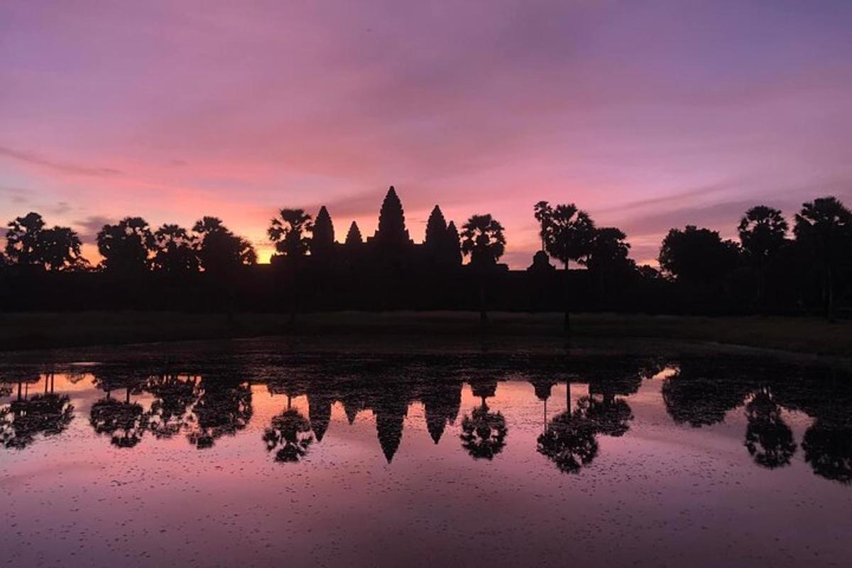 matahari terbenam di atas kolam di hadapan kuil