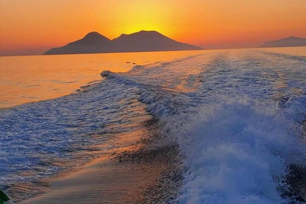 a boat in the ocean with the sunset in the background