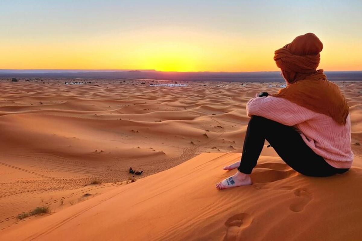 a woman sitting in the desert watching the sunset