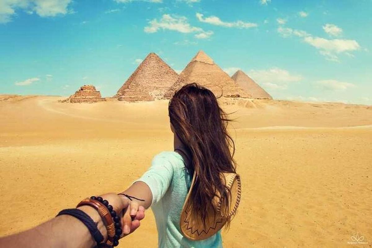 một người đàn ông và một người phụ nữ nắm tay nhau trước kim tự tháp