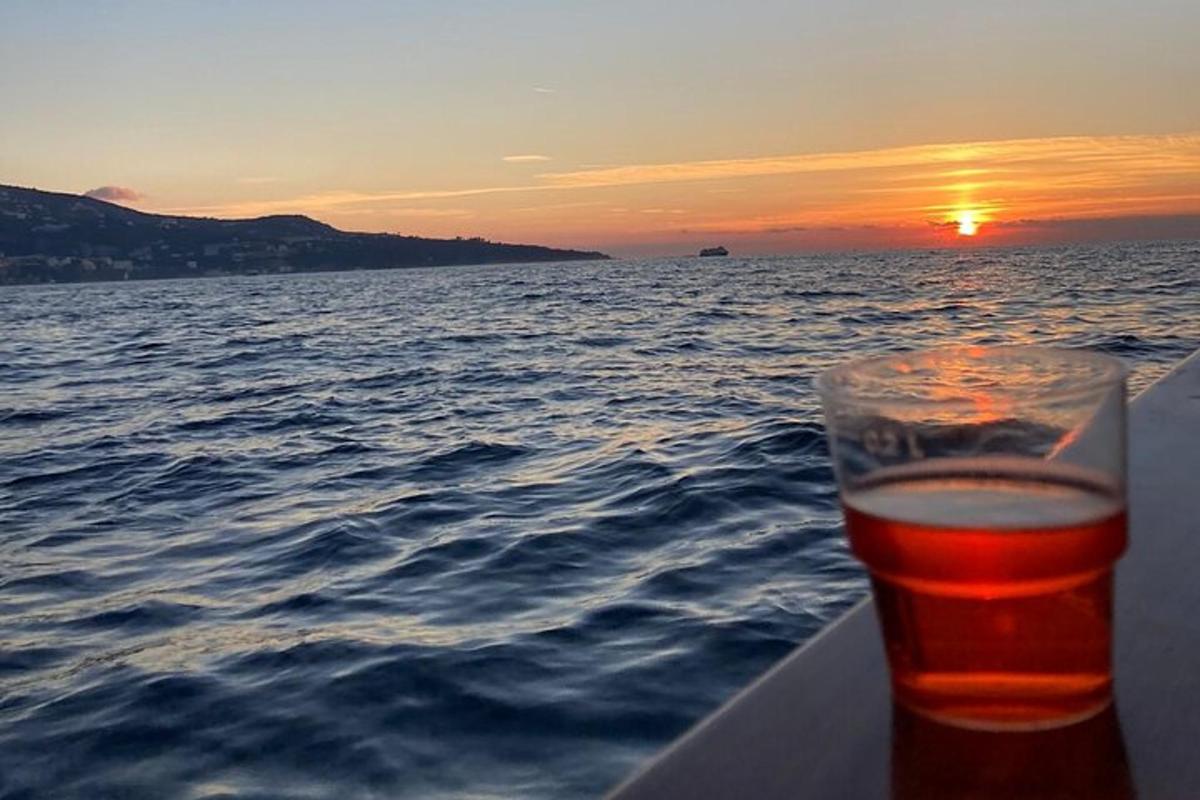 sklenice piva sedí na lodi se západem slunce