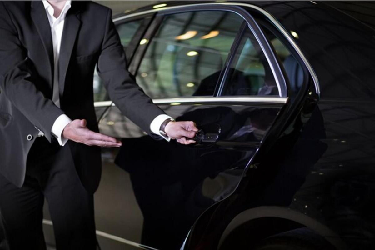 een man in pak die naast een auto staat