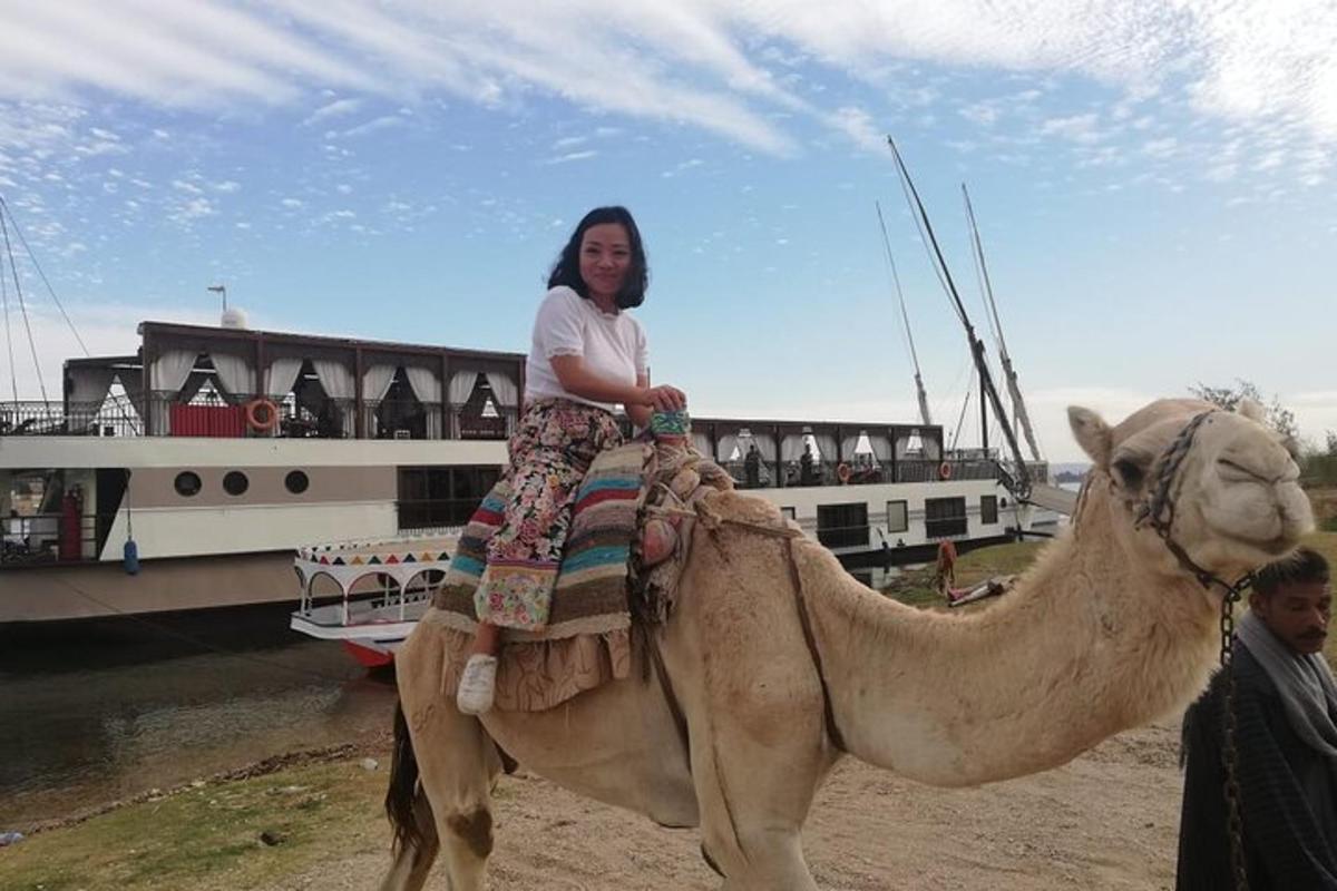a woman riding on a camel next to a boat