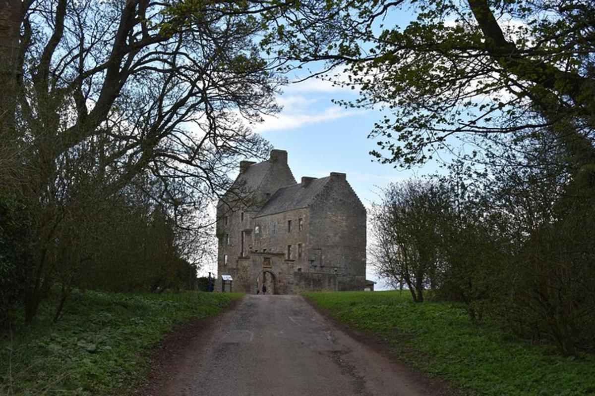 an old castle in a field with a dirt road