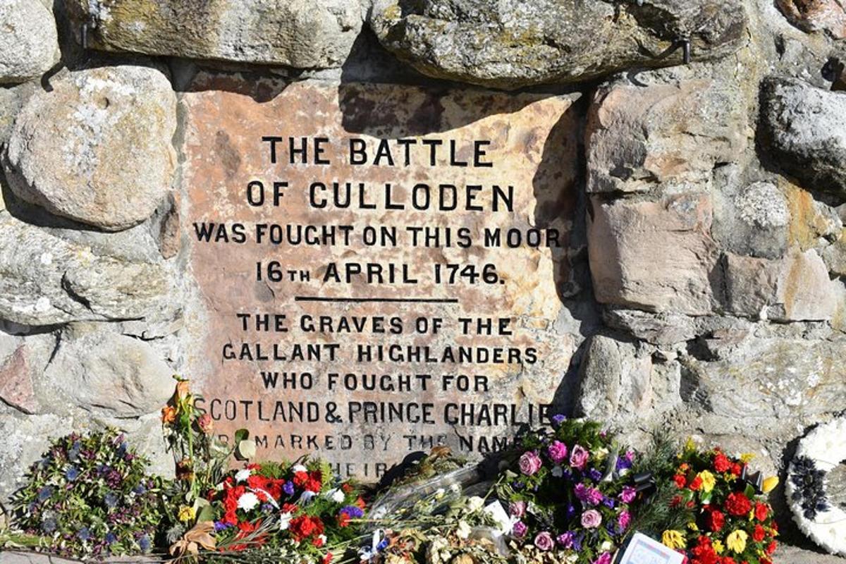 a sign on a stone wall with flowers