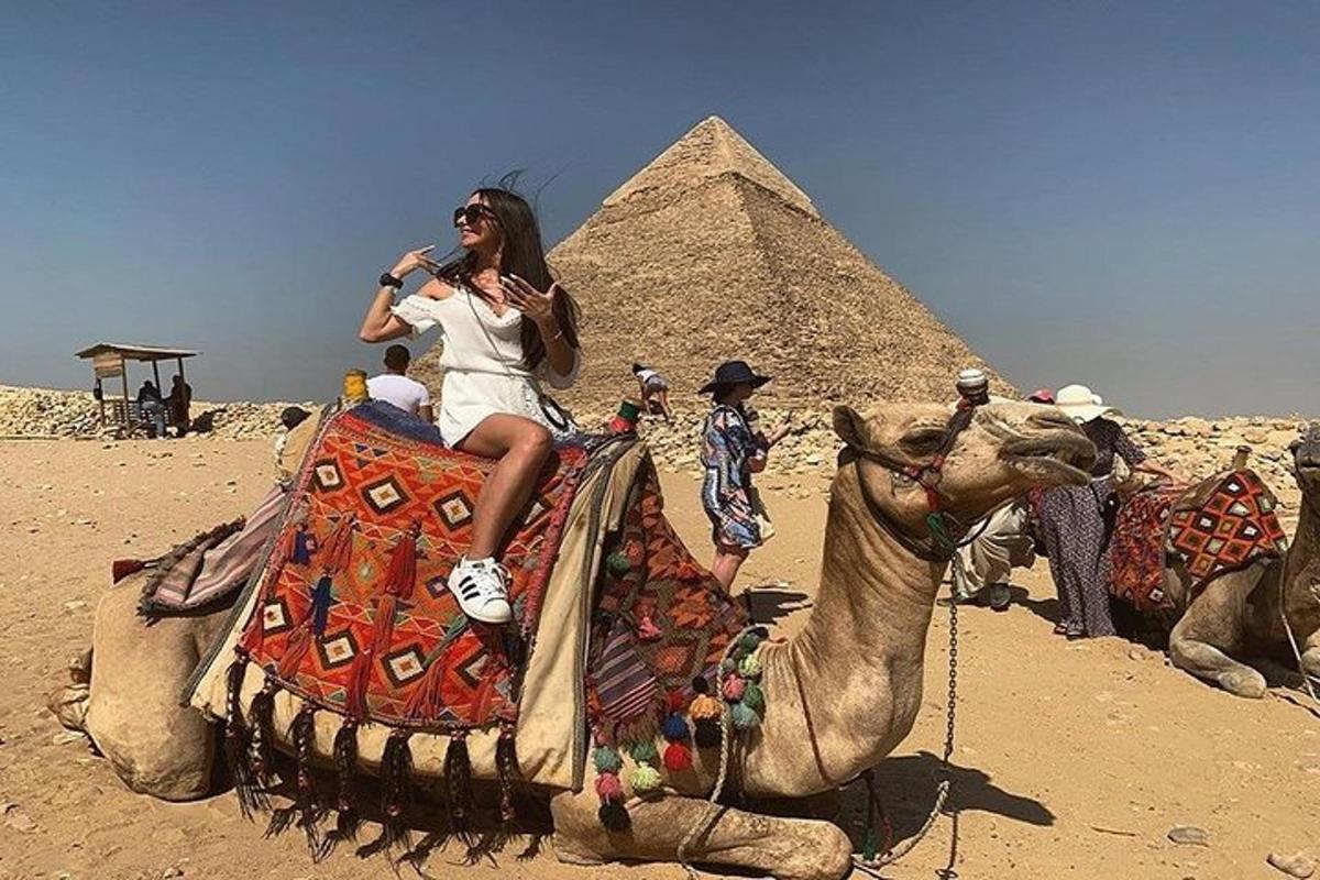 žena jazdiaca na ťave pred pyramídami