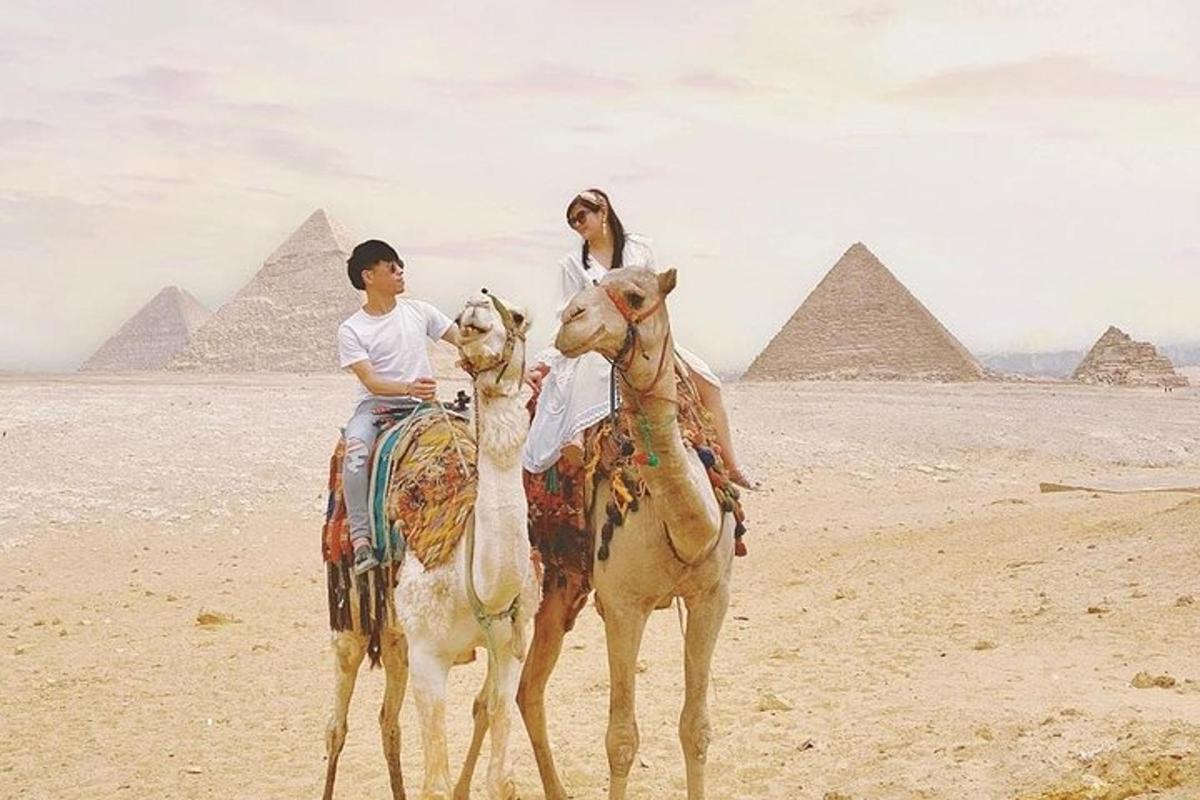 to personer som rir på kameler foran pyramidene