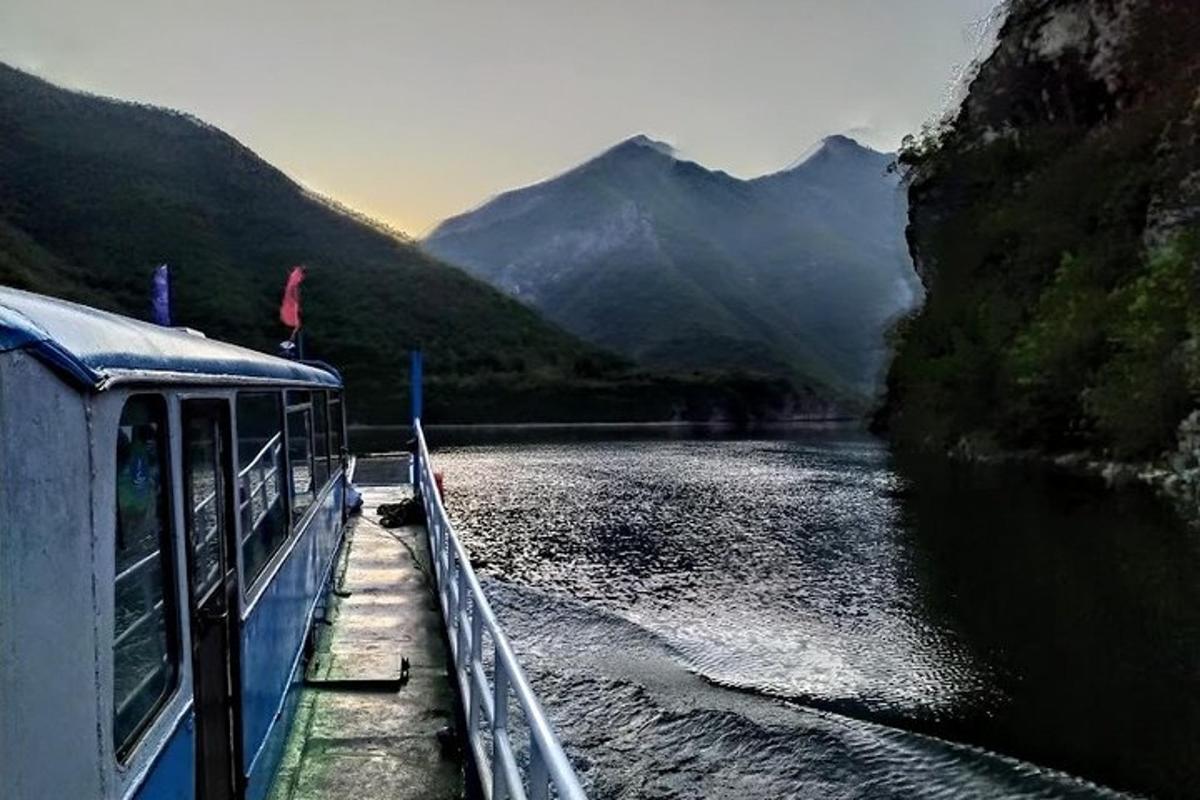 sebuah perahu di sungai dengan pegunungan di latar belakang