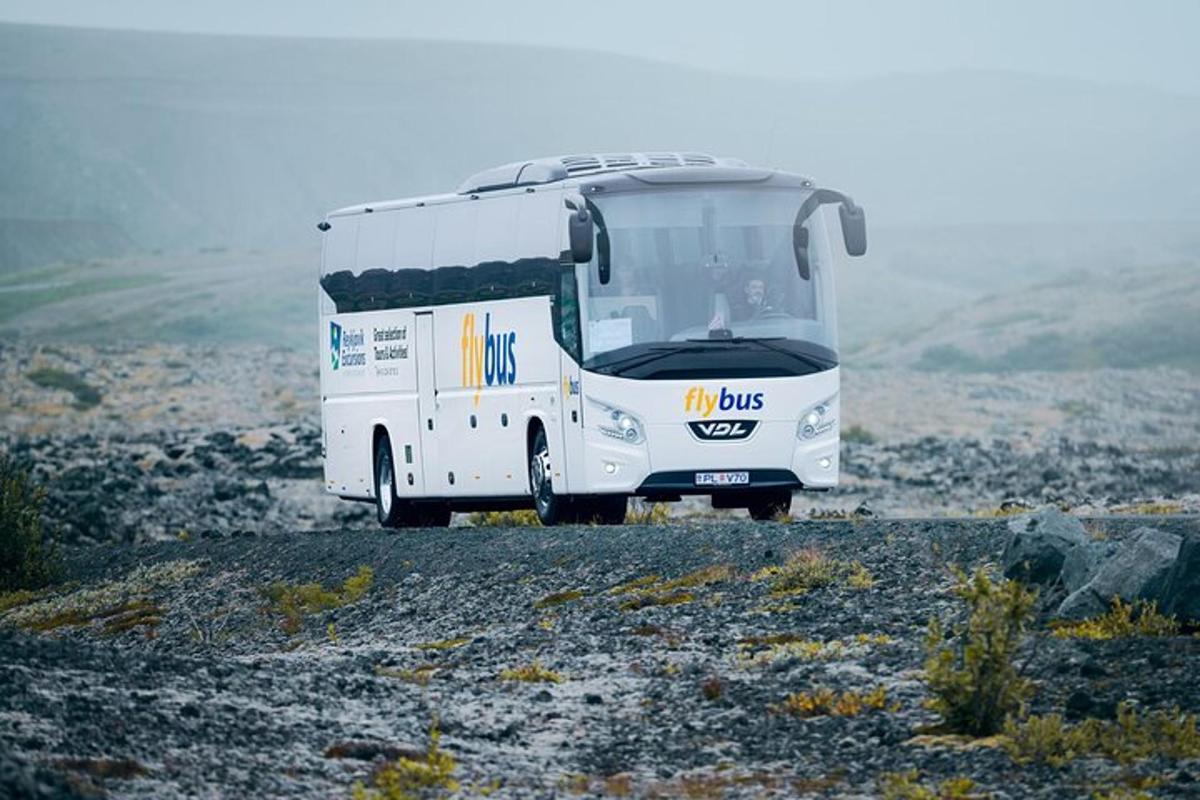 a white bus is parked on a rocky field