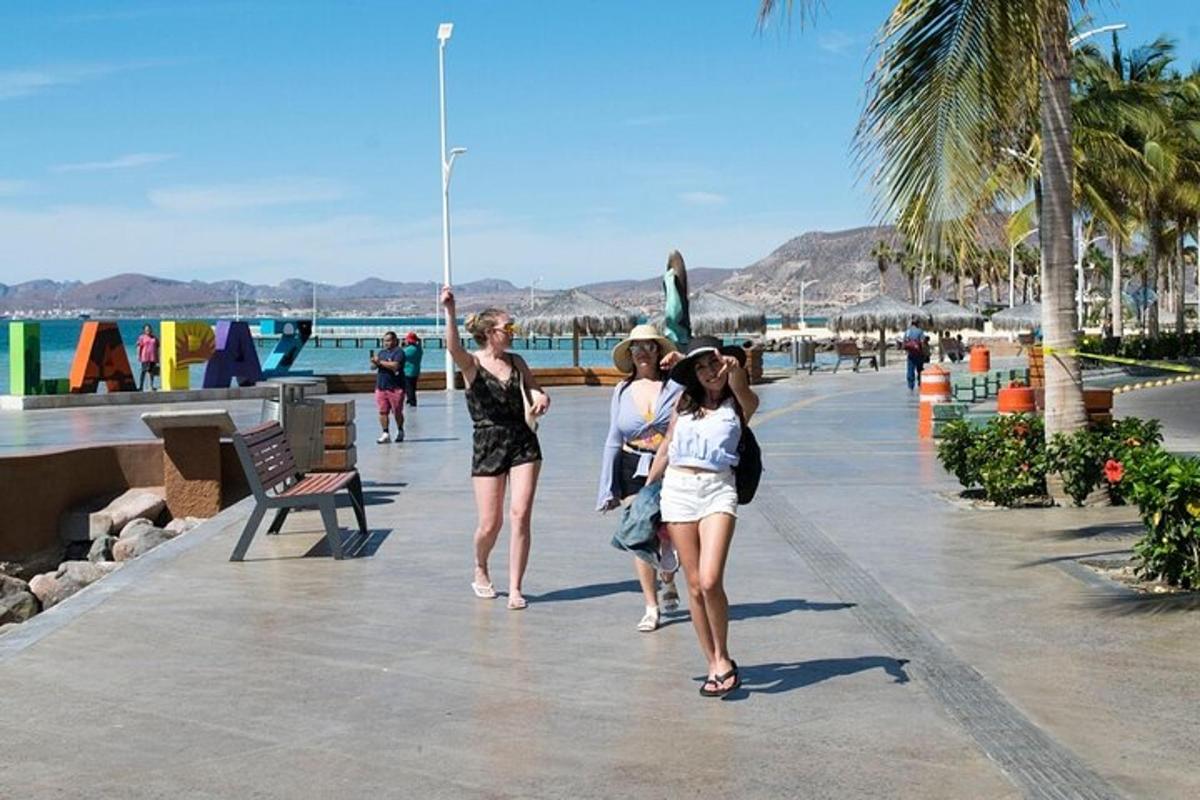 a group of women walking down a sidewalk near the beach