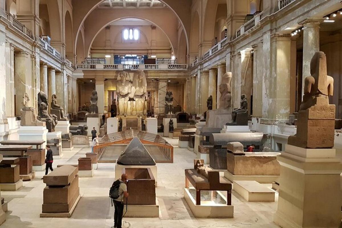 Un museo con gente de pie en una gran sala con estatuas.