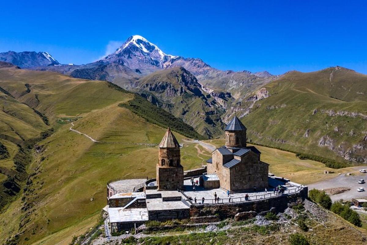an old church on a hill with mountains in the background