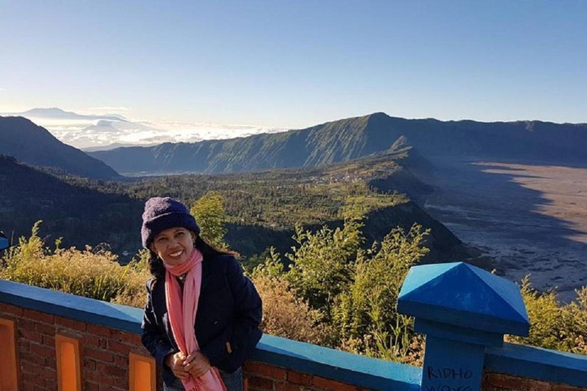 seorang wanita berdiri di atas dinding dengan pemandangan gunung