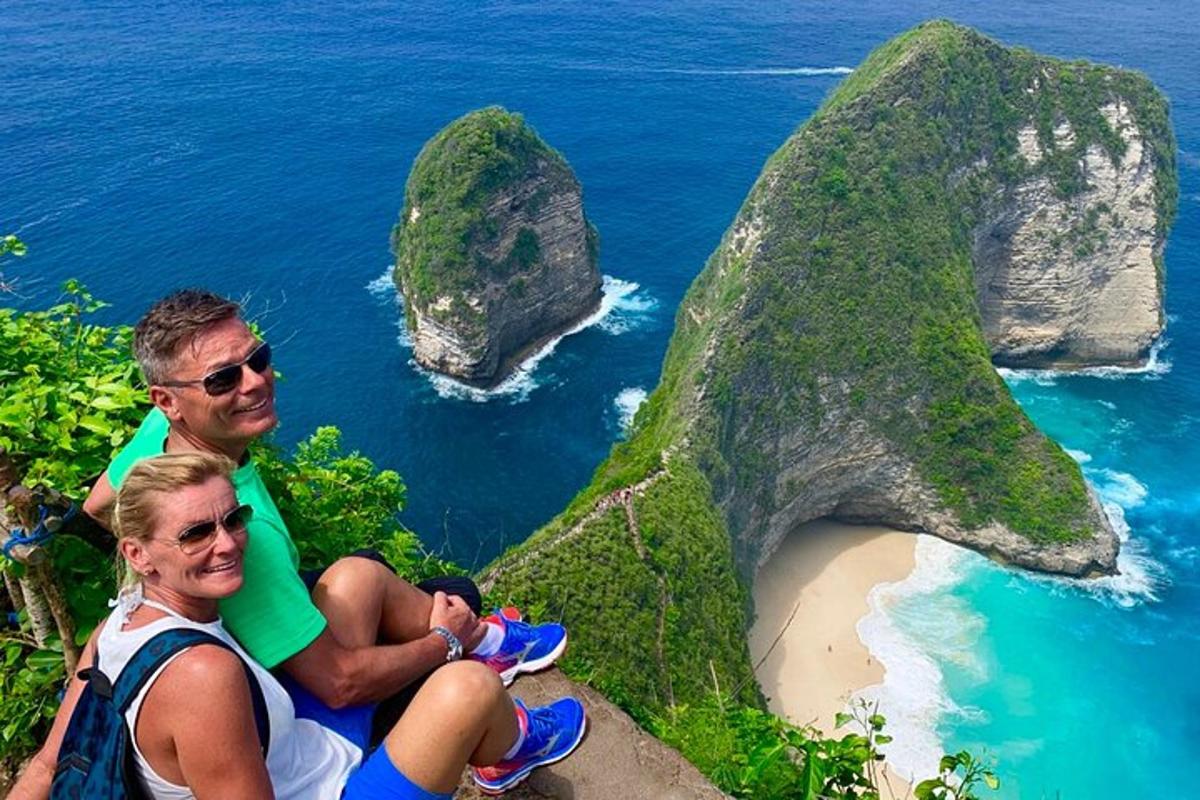 zwei Personen sitzen auf einem Felsen mit Blick auf den Ozean
