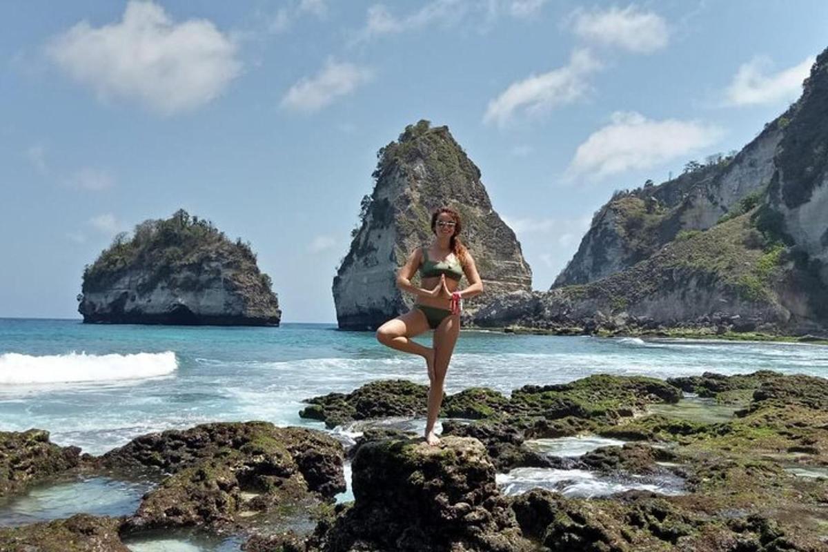 Una mujer en bikini parada sobre las rocas en la playa.