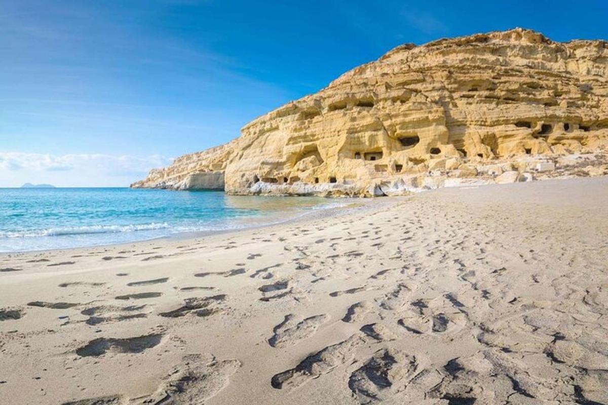 plaża ze śladami stóp na piasku obok klifu