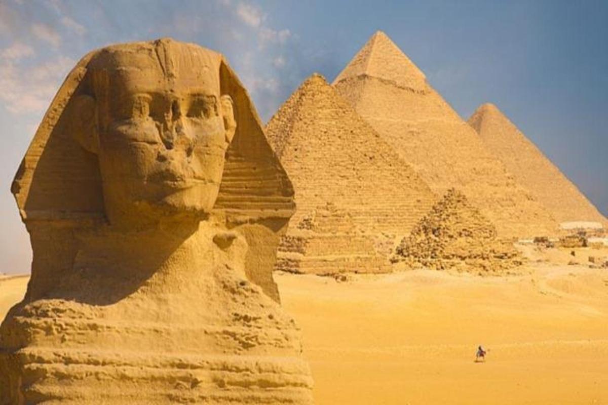 uma estátua em frente às pirâmides no deserto