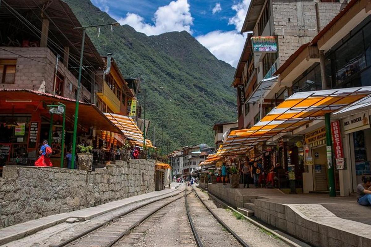 una strada con binari del treno in una città con una montagna