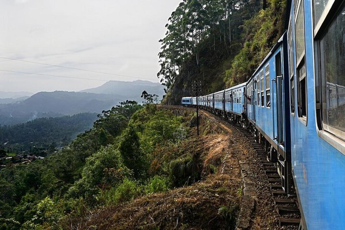 a blue train traveling down a hill on a mountain