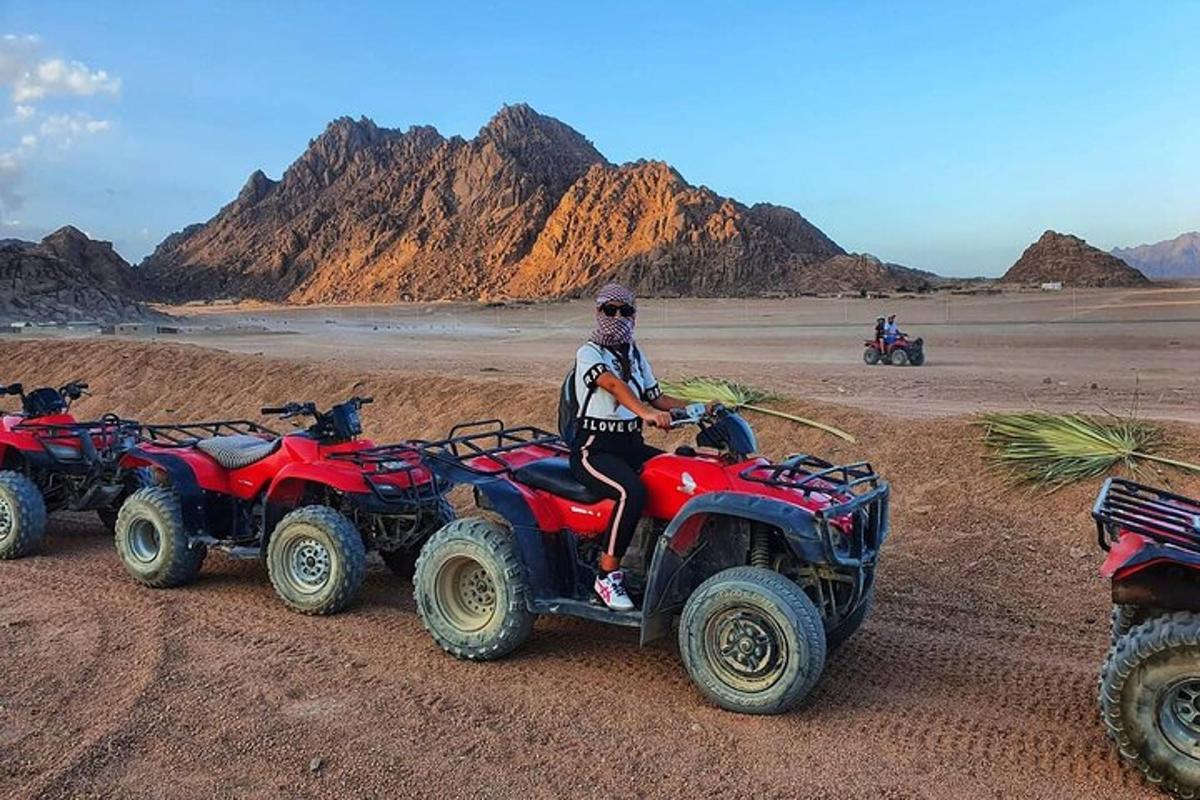 un home assegut en un quad al desert