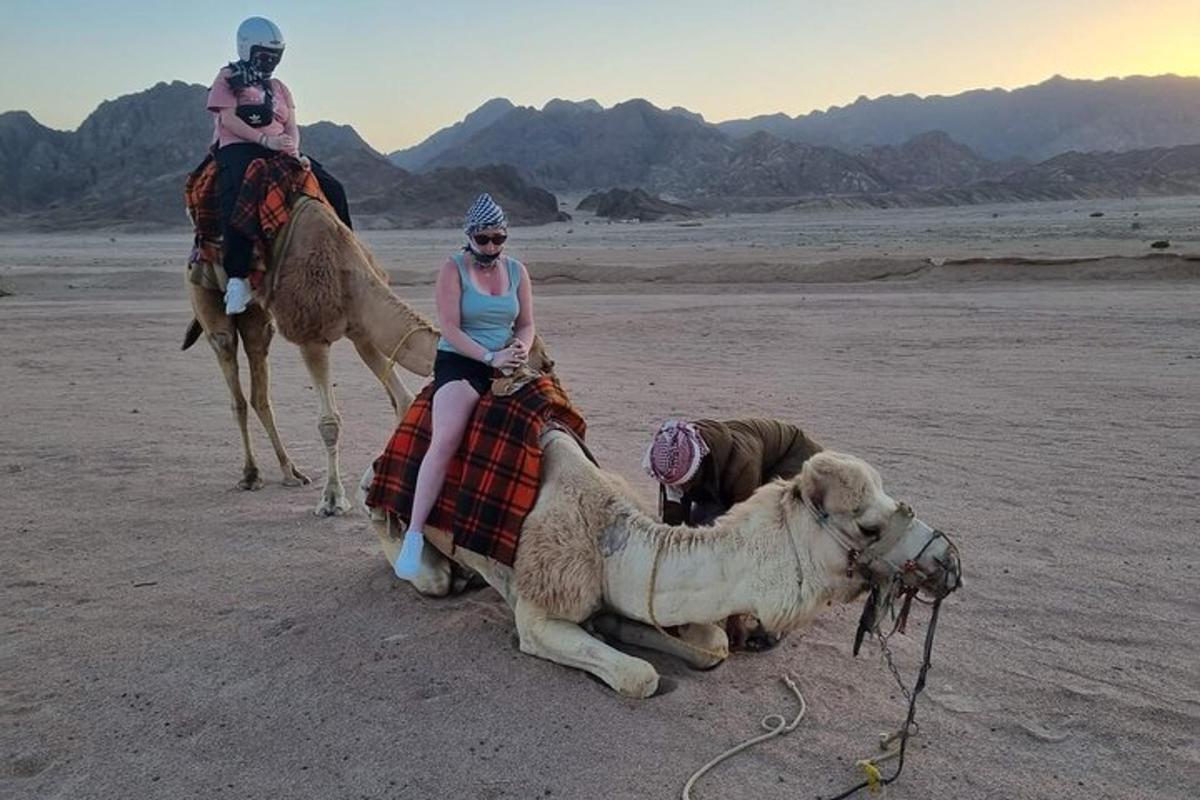 dues dones en camells i un gos al desert